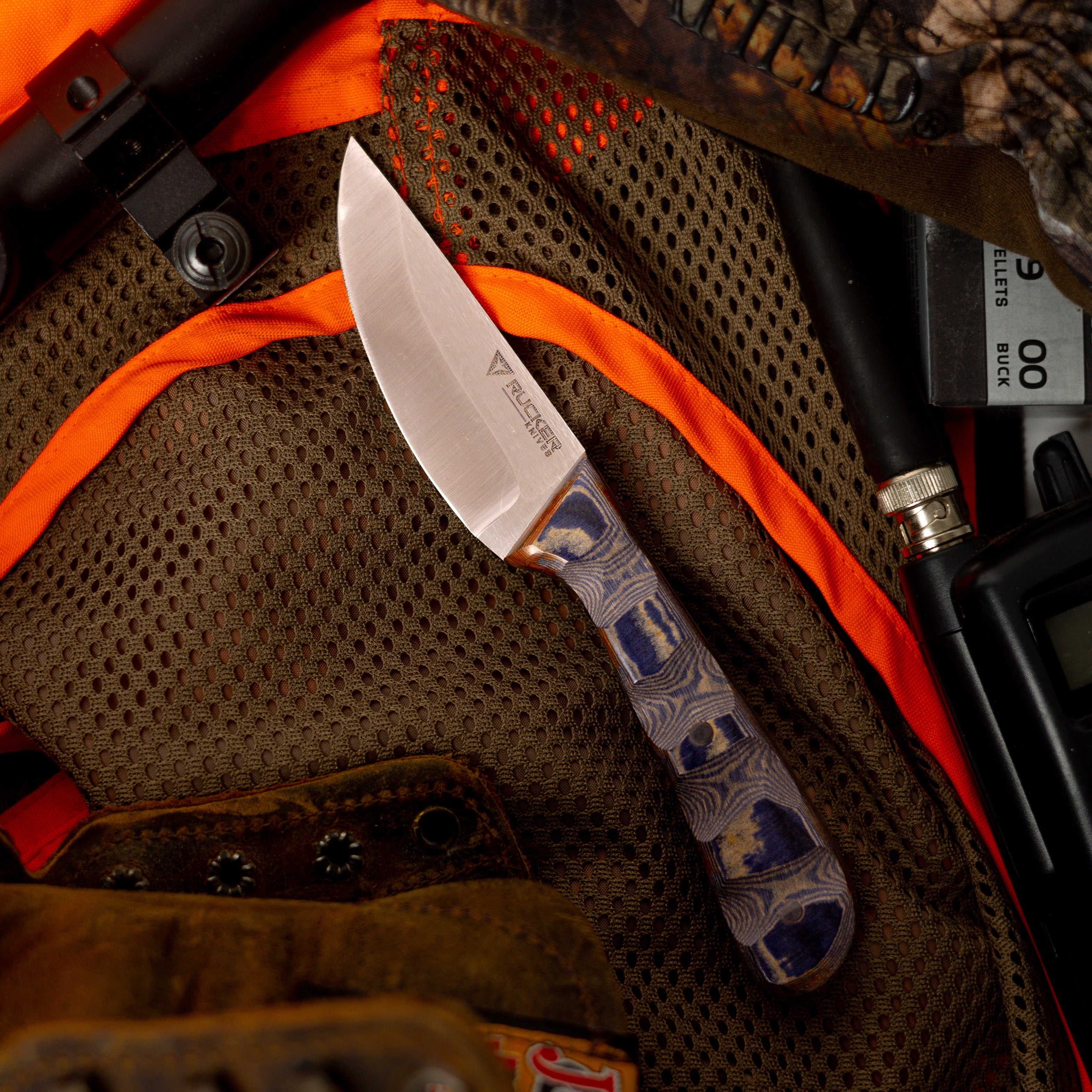 Rucker Knife Talon Knife staged background on hunting vest, camoflouge, and radio